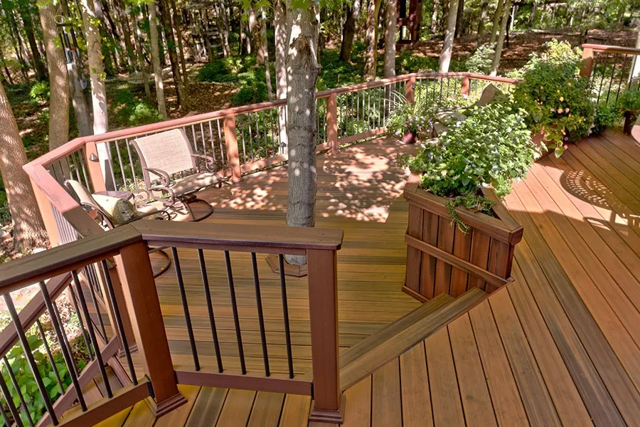 Multi-level deck with railings and built-in planter around mature trees